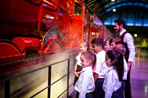 School children stood next to the Hogwarts Express train on Platform 9 ¾